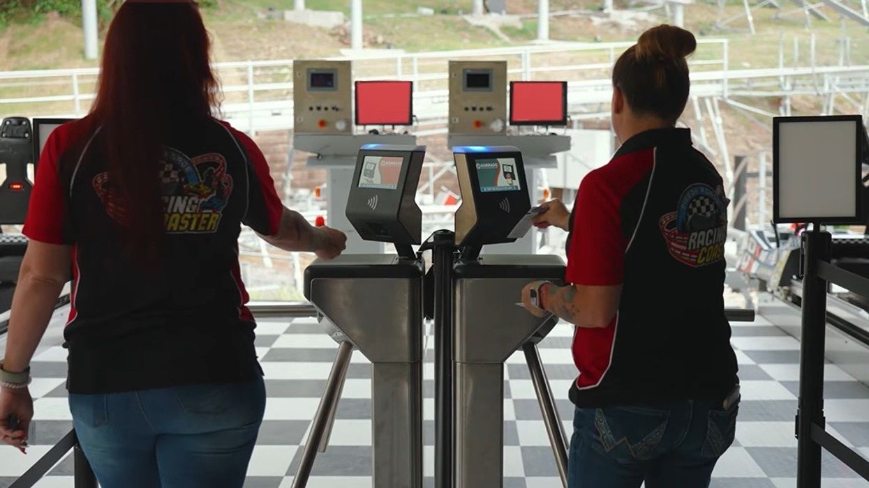 Two people at turnstiles with gadget in a racing-themed venue.