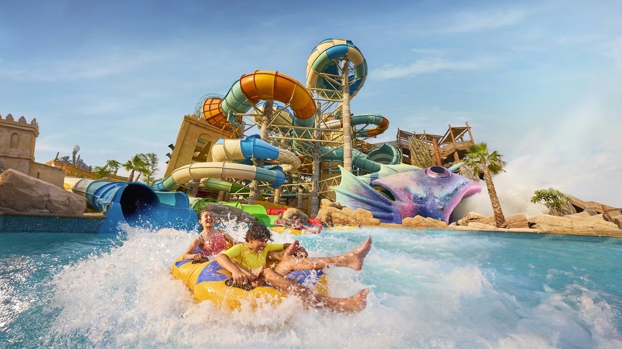 Two people enjoy a ride down a vibrant water slide at Yas Waterworld