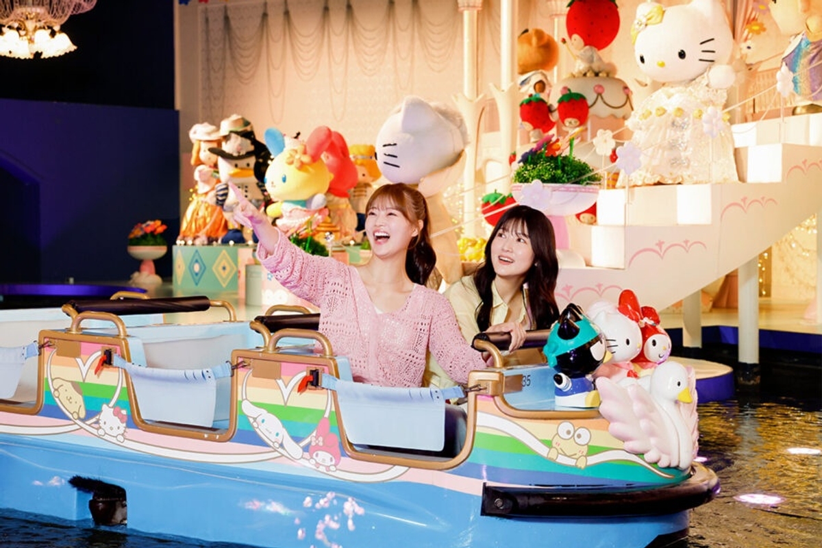 Two people enjoying a Sanrio-themed boat ride with colorful Hello Kitty statues.