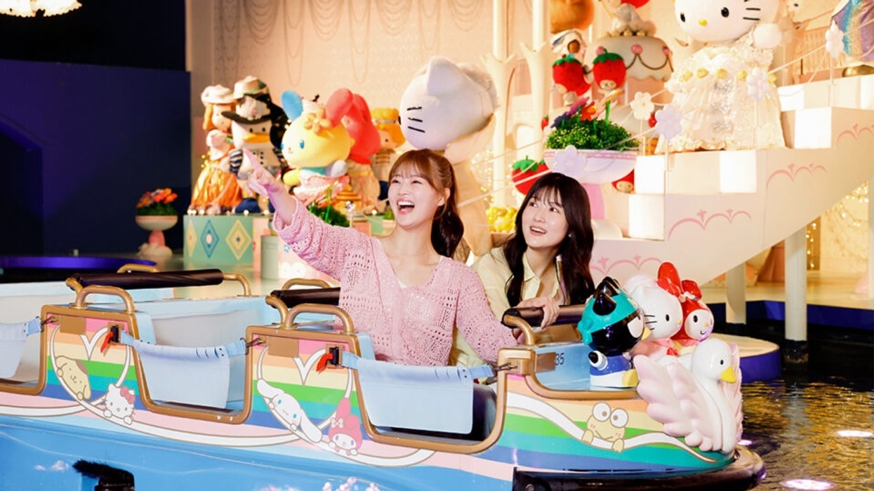 Two people enjoying a Sanrio-themed boat ride with colorful Hello Kitty statues.
