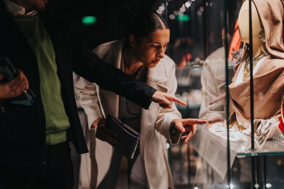 Two people examine a museum exhibit behind glass.