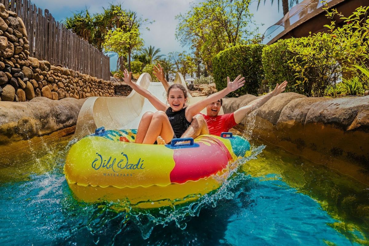 Two people in a colorful raft enjoying a water slide at Wild Wadi Waterpark.