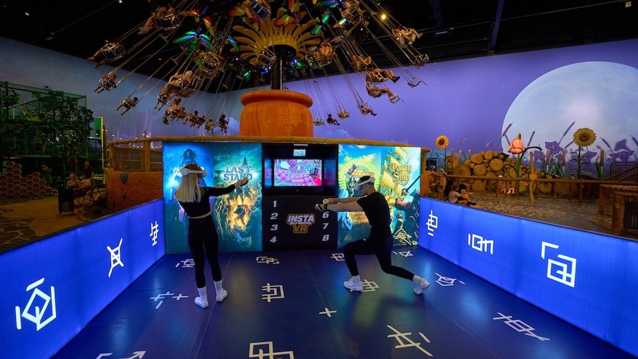 Two people in a VR arcade with vibrant decor and a swing ride above.