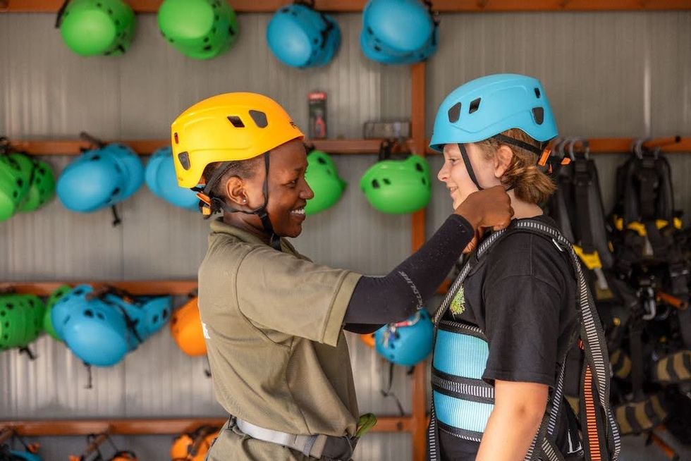 Two people in helmets prepare for a climbing activity with harnesses at Fujairah Adventure Park