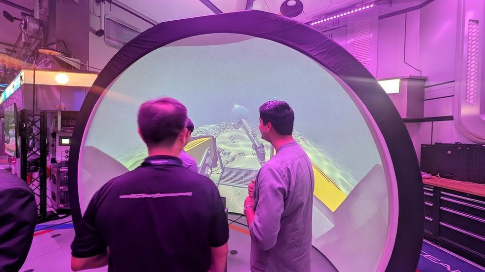 Two people interact with a dome-shaped virtual reality display in a tech-lit room.