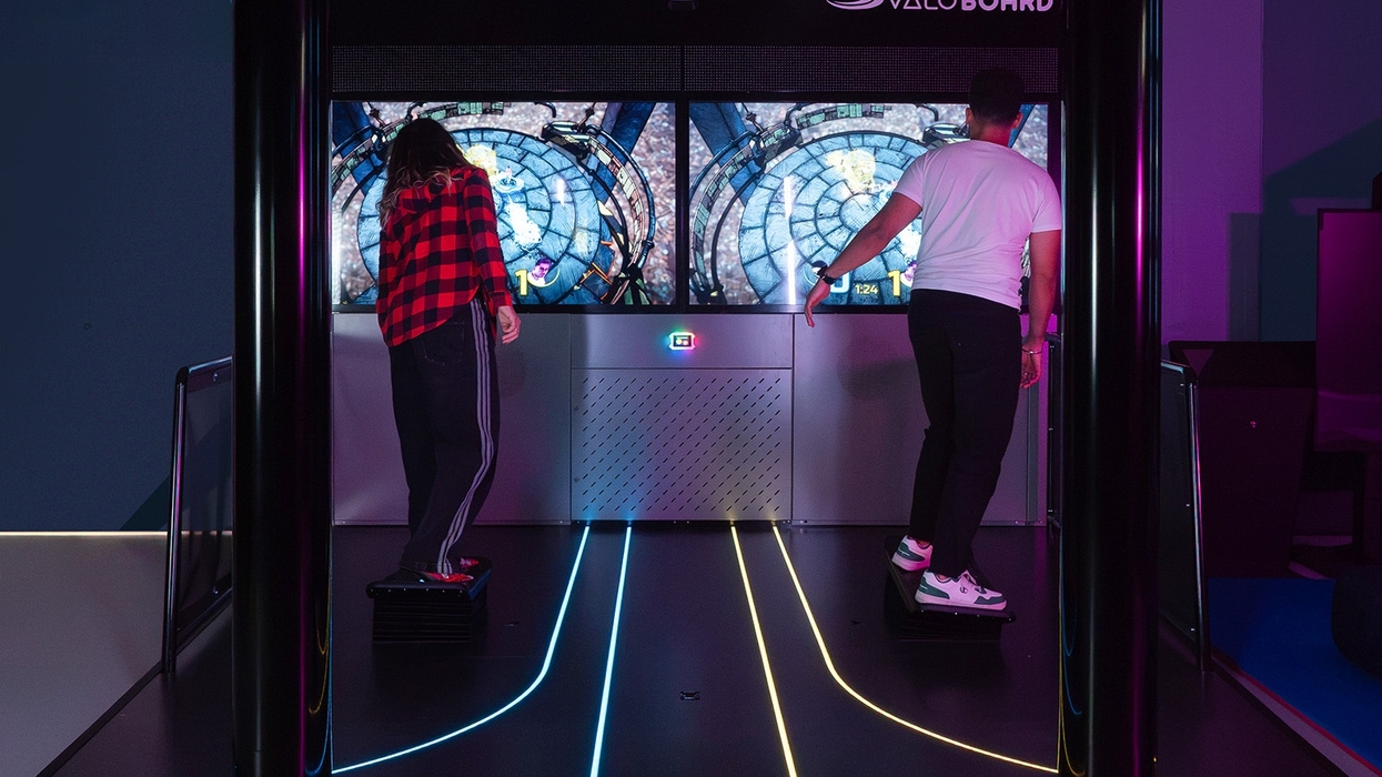 Two people playing a virtual reality game on ValoBoard with glowing floor lines.