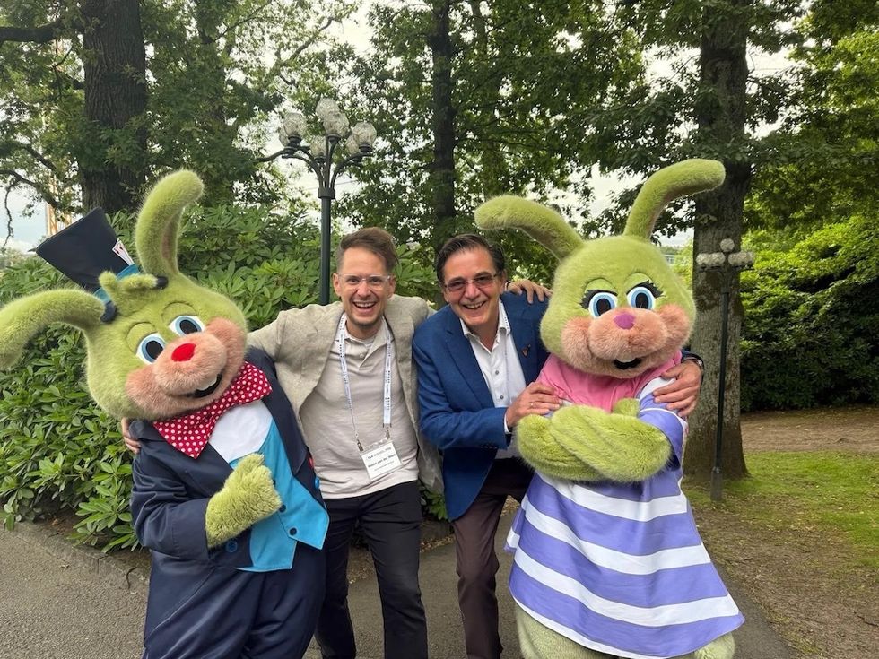 Two people pose with giant rabbit mascots in a park.