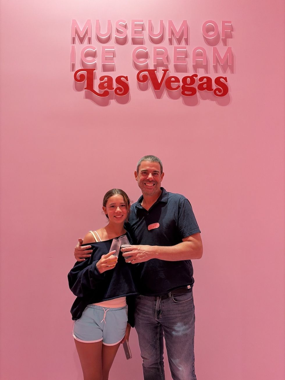 Two people smiling at the Museum of Ice Cream in Las Vegas with pink background.