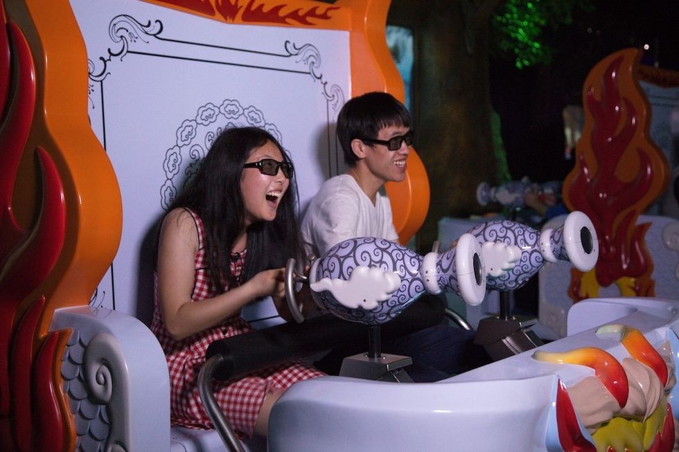 Two people smiling on an amusement ride, wearing 3D glasses.