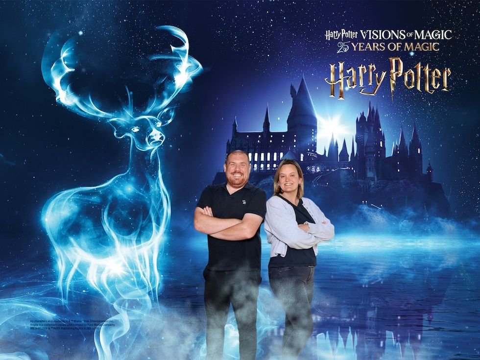 Two people smiling with a stag Patronus and Hogwarts castle in the background.