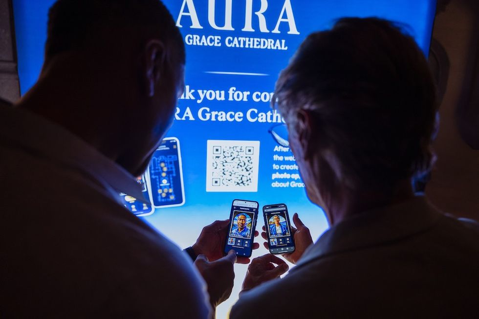 Two people use phones in front of a bright "AURA Grace Cathedral" sign.