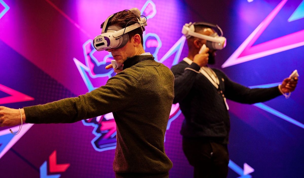 Two people using VR headsets and controllers in a neon-lit room.