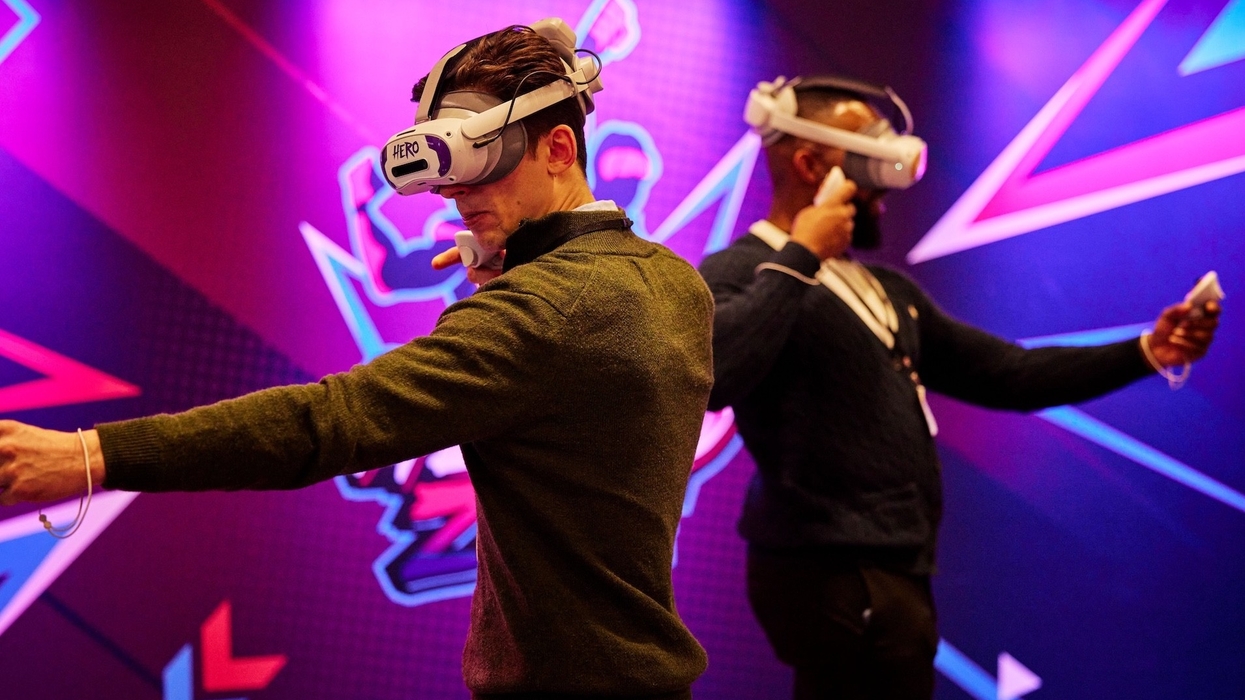 Two people using VR headsets and controllers in a neon-lit room.