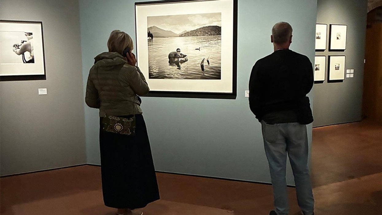 Two people viewing framed photographs in an art gallery.