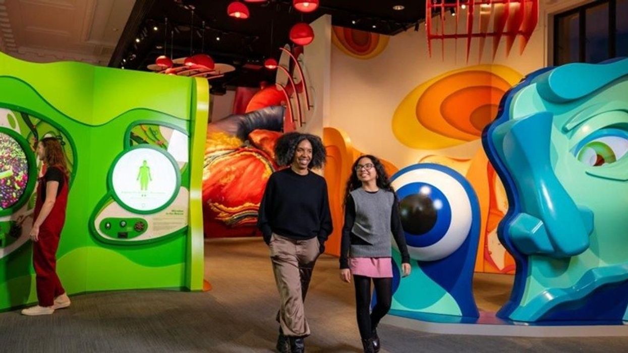 Two people walking through a colorful, interactive science exhibit.