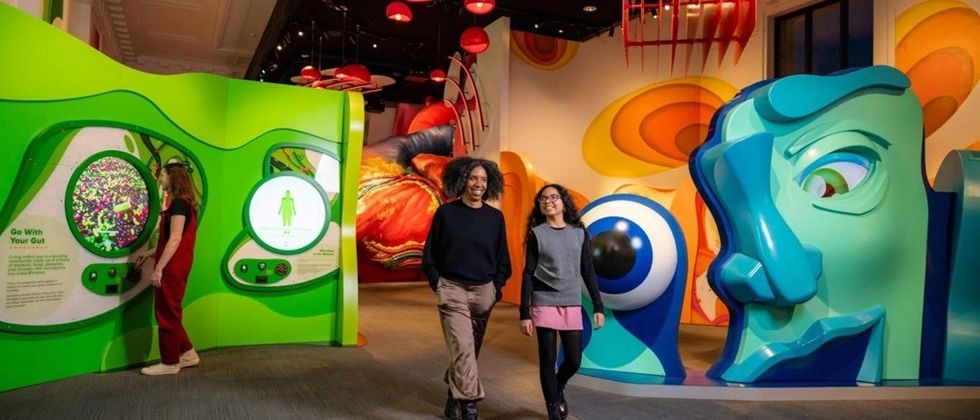 Two people walking through a colorful, interactive science exhibit.