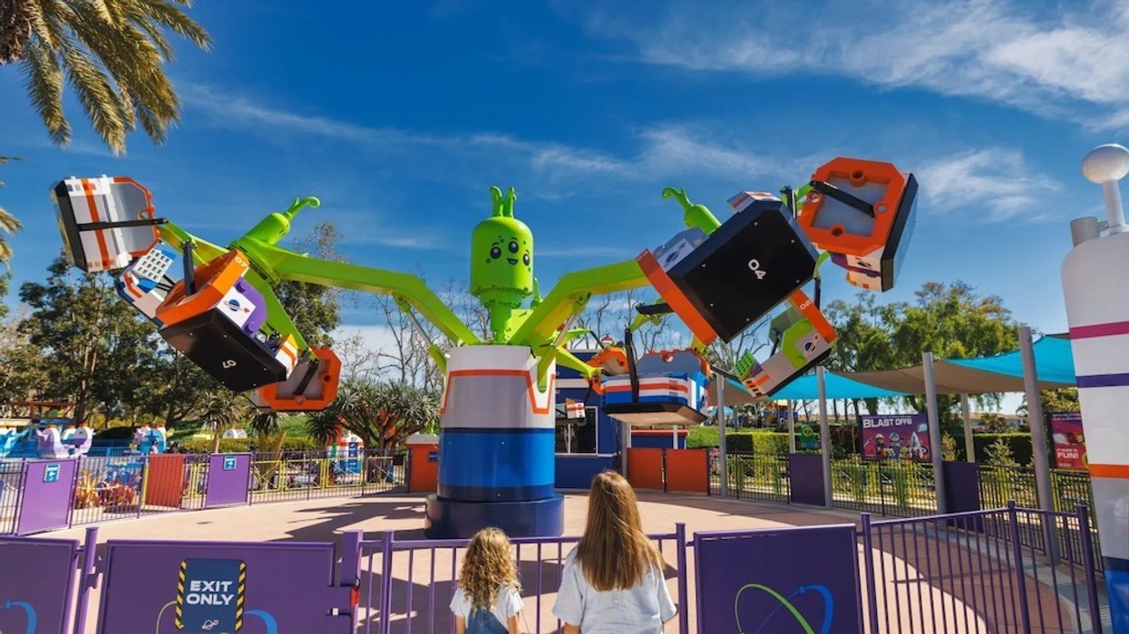 Two people watching a colorful, robot-themed amusement park ride.