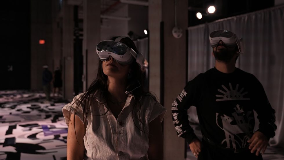 Two people wearing VR headsets in a dimly lit room.