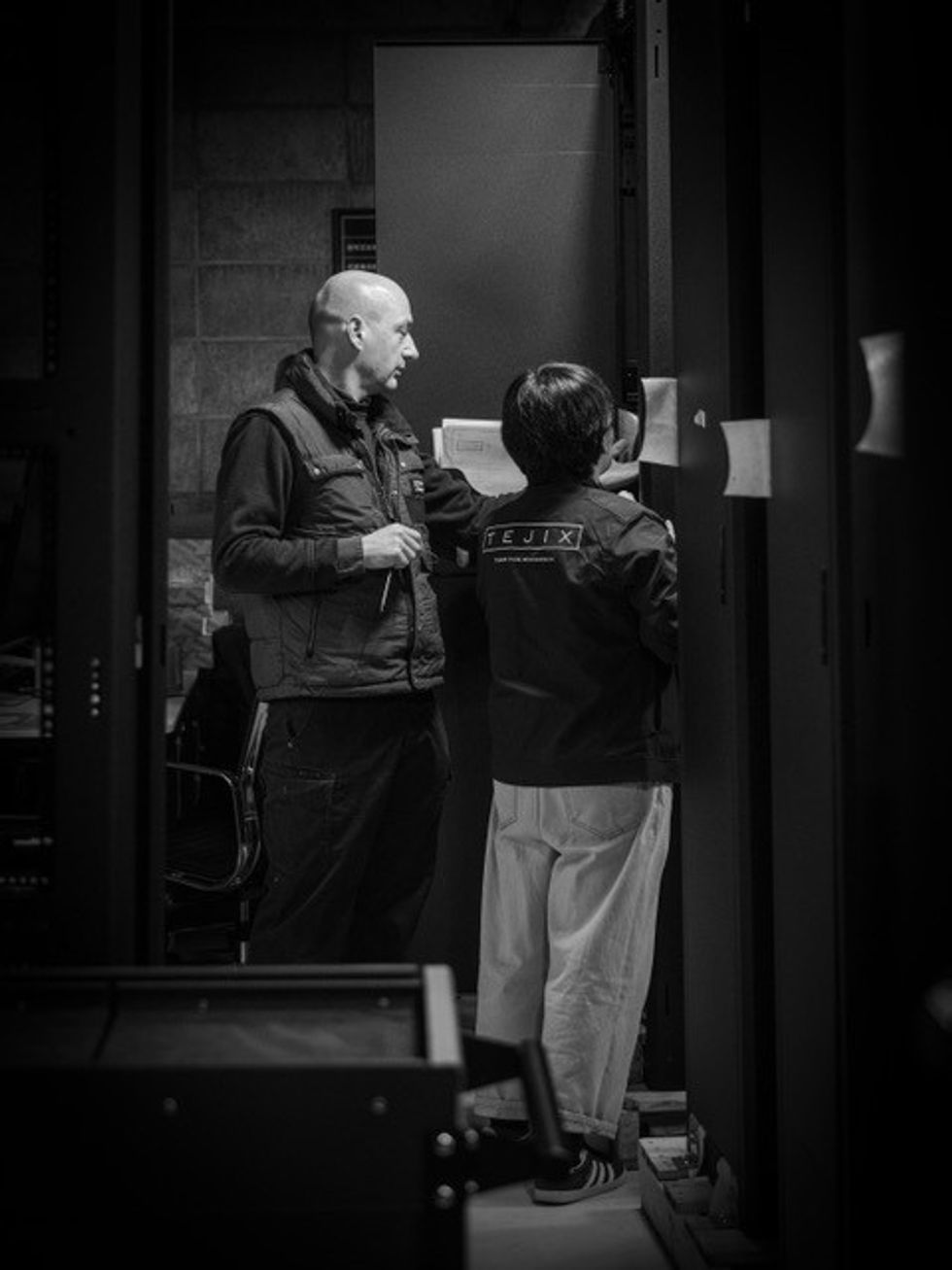 Two people working at a server rack in a dimly lit room.