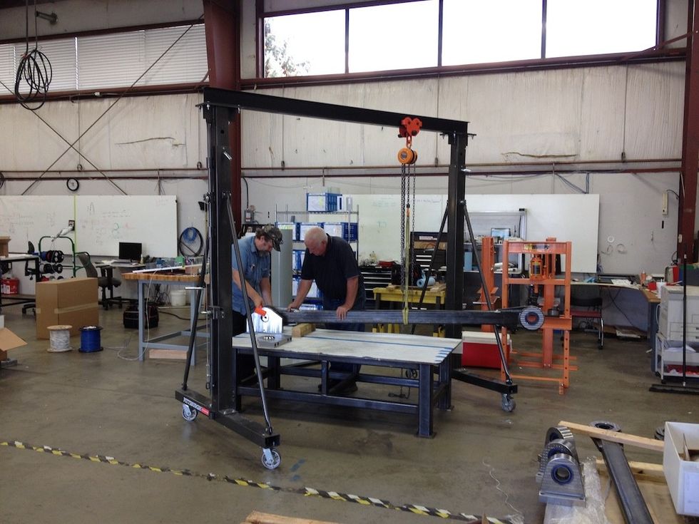 Two people working on machinery in a large industrial workshop.