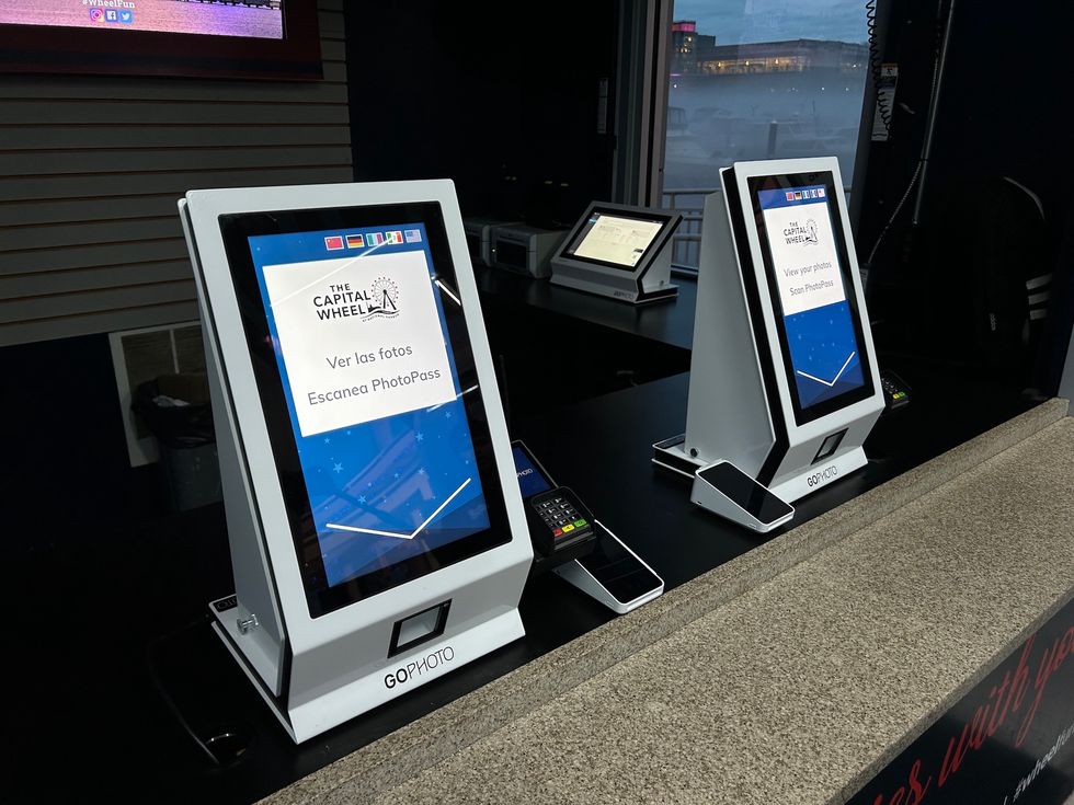 Two photo kiosk stations with screens for viewing and scanning PhotoPass images.