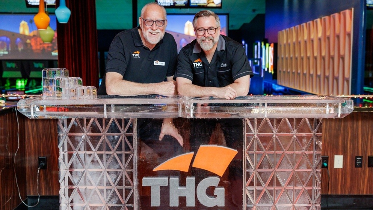 Two smiling people behind a branded THG Creative ice sculpture.