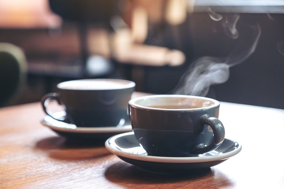 Two steaming coffee cups on a wooden table in a cozy setting.