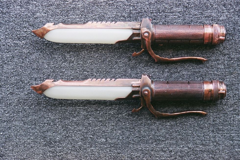 Two vintage-style retractable blade knives on a textured gray surface.