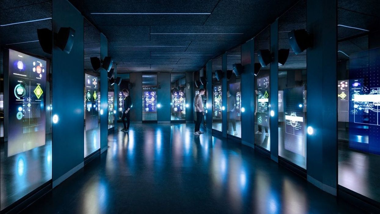 Two visitors reading the digital wall panels at the Spyscape museum