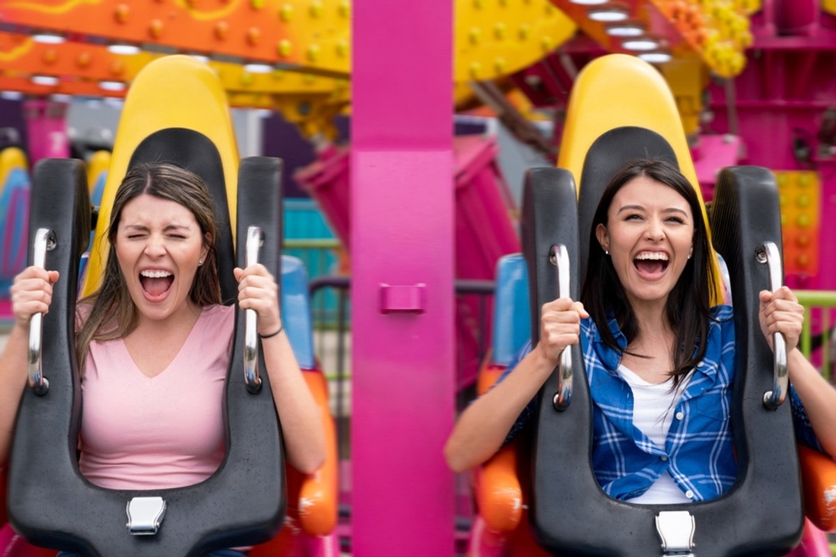 Two women excitedly riding a colourful amusement park ride.