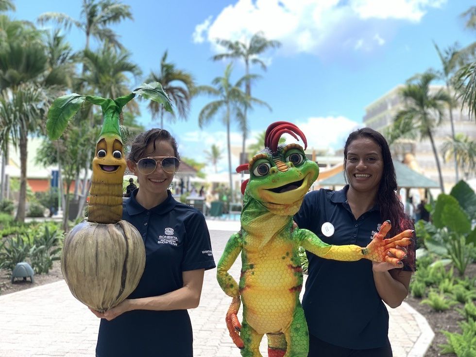 Two women holding colorful cartoon character puppets outdoors.