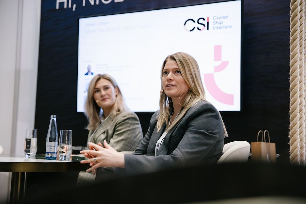 Two women speaking at a conference panel about cruise ship interiors.