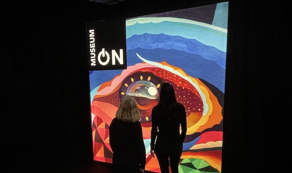 Two women stand in front of lit sign for MuseumON retailtainment