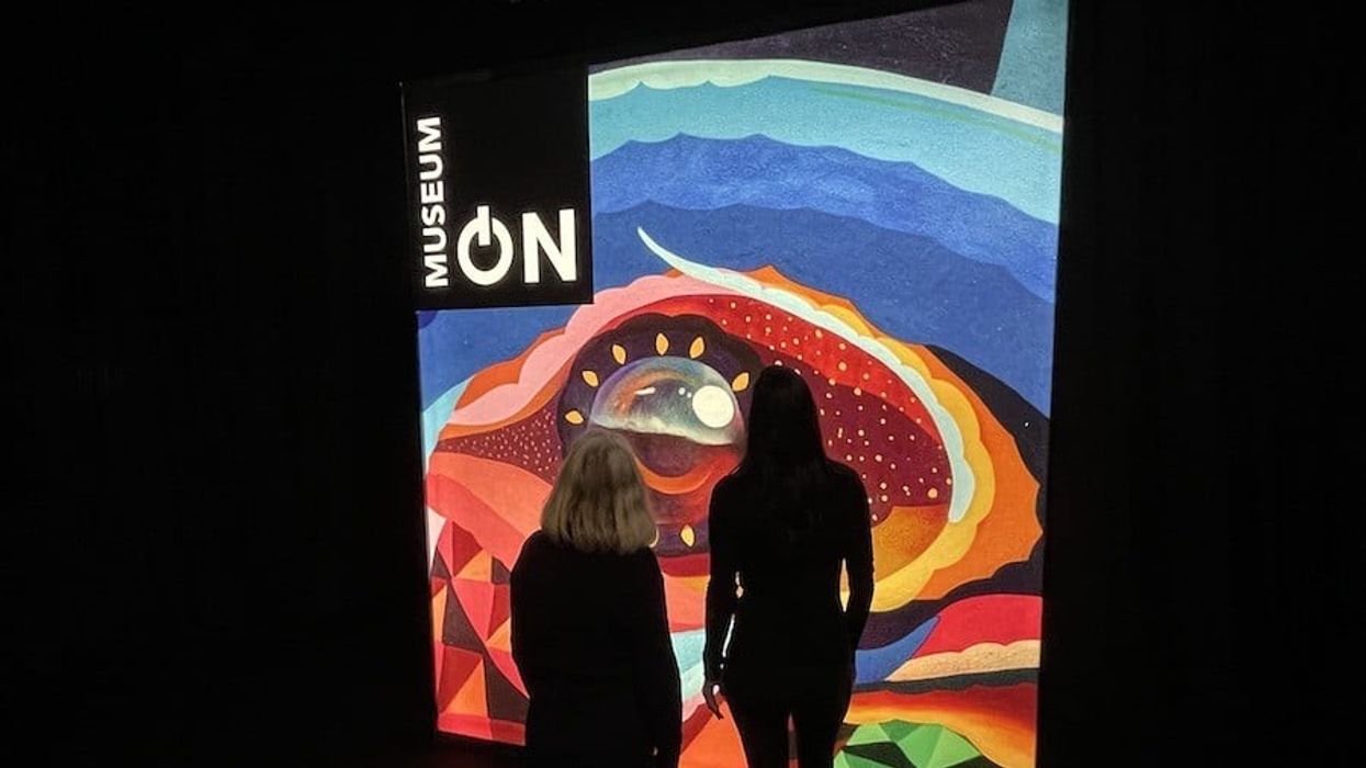 Two women stand in front of lit sign for MuseumON