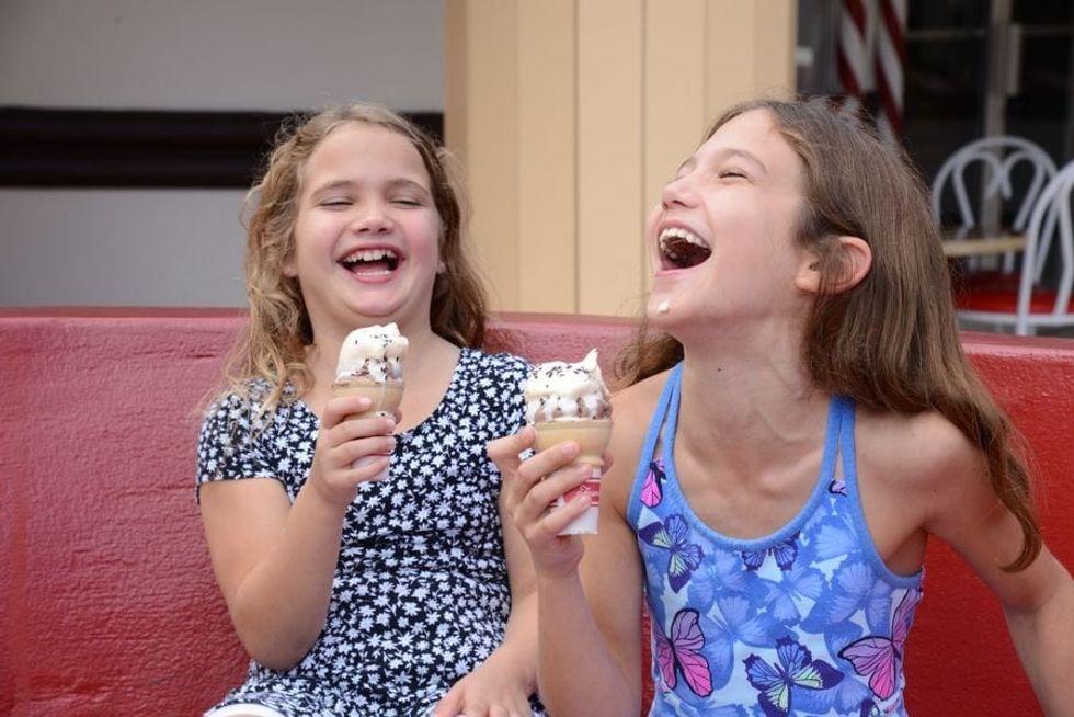 Two young girls laughing and eating ice cream at Give Kids The World
