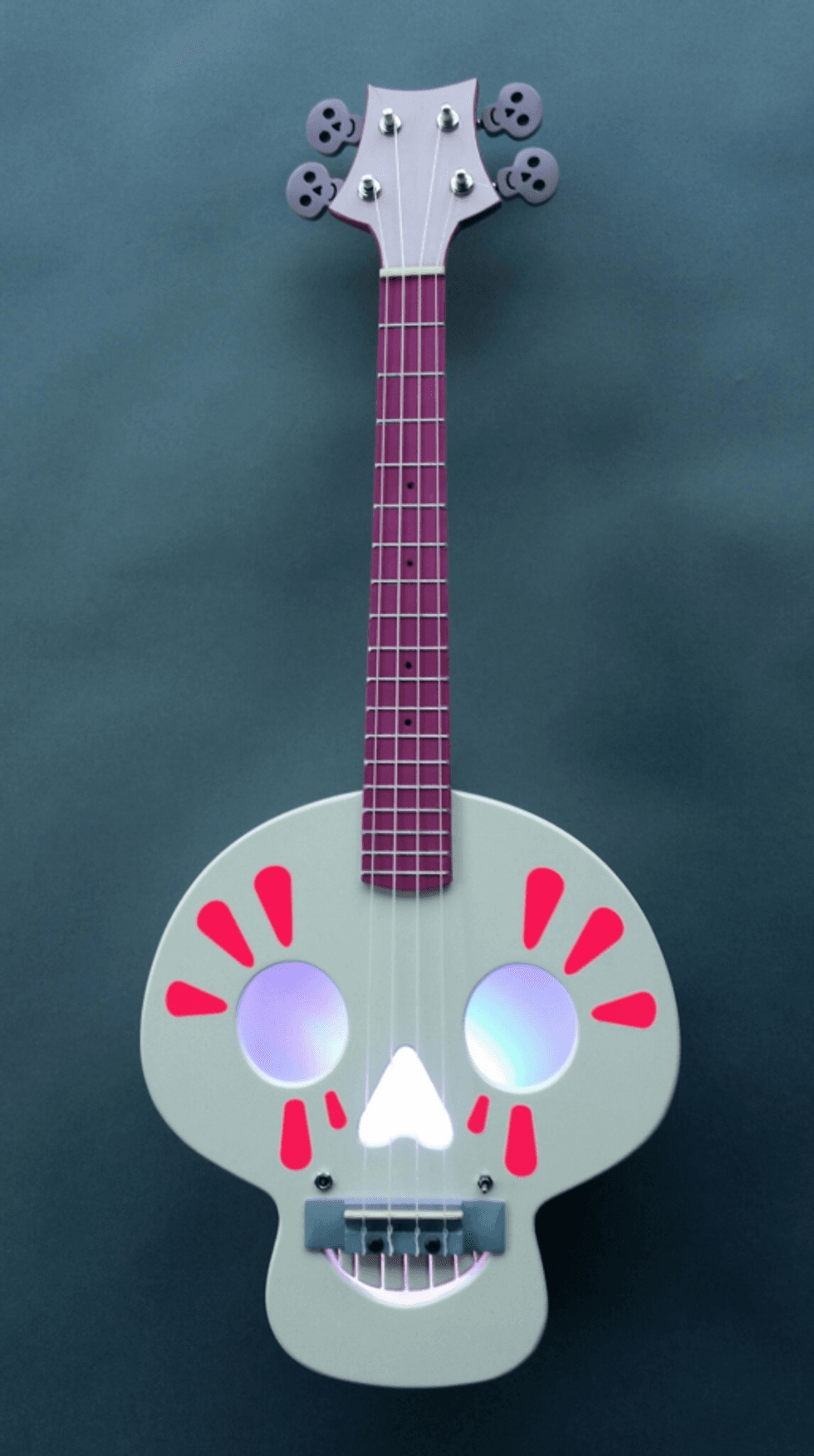 Ukulele with a skull-shaped body and purple neck on a dark background.