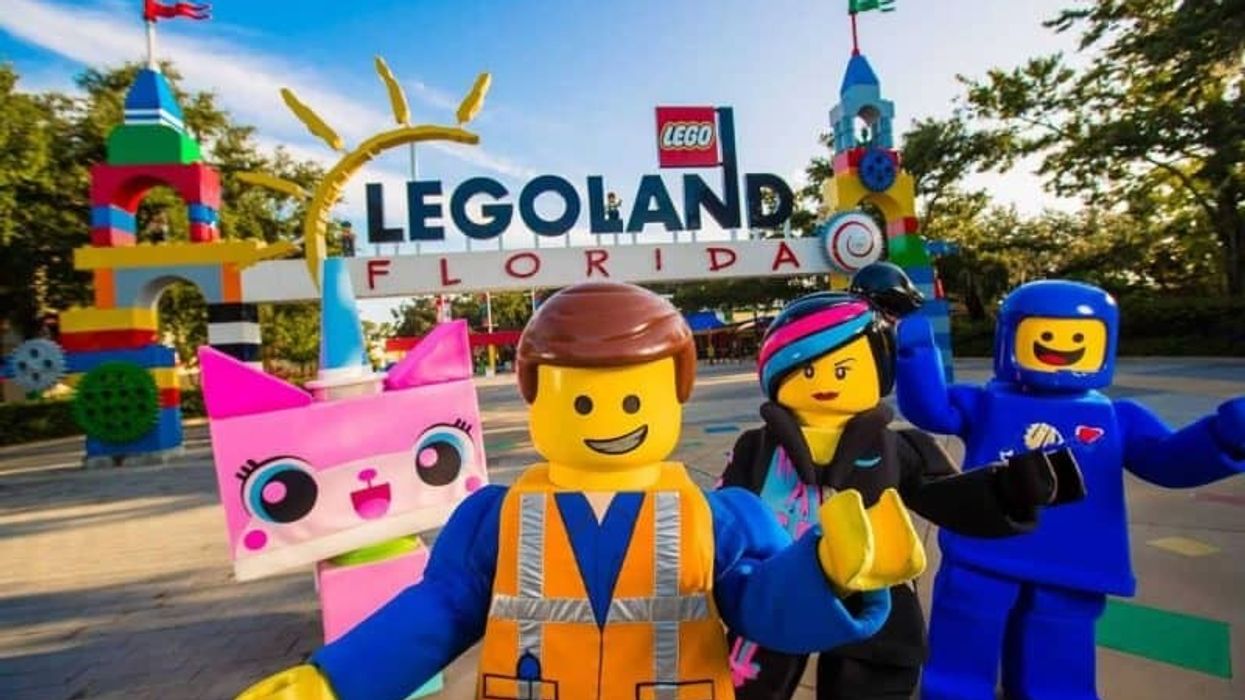 Unikitty, Emmet, Wyldstyle and Benny from THE LEGO MOVIE WORLD posing in front of Legoland Florida entrance