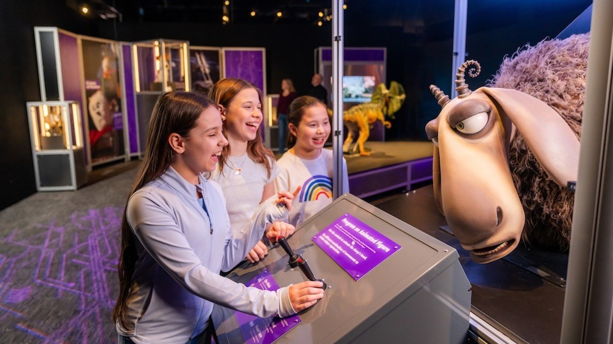 Universal Theme Parks: The Exhibition - Three girls interacting with an animated exhibit in a museum setting.