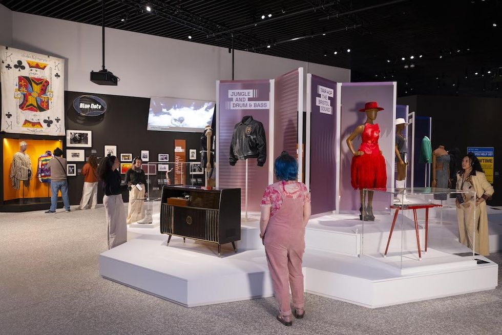 V&A East Museum exhibit with fashion and music memorabilia displays, including jackets and a red dress.
