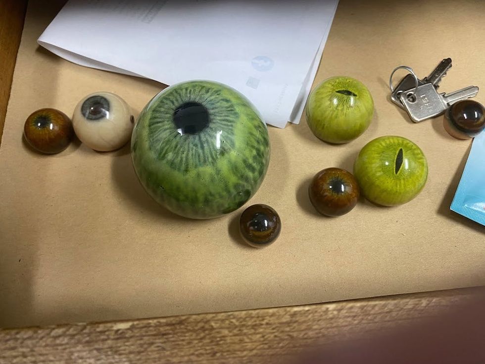 Various glass eyeballs and keys on a wooden surface.