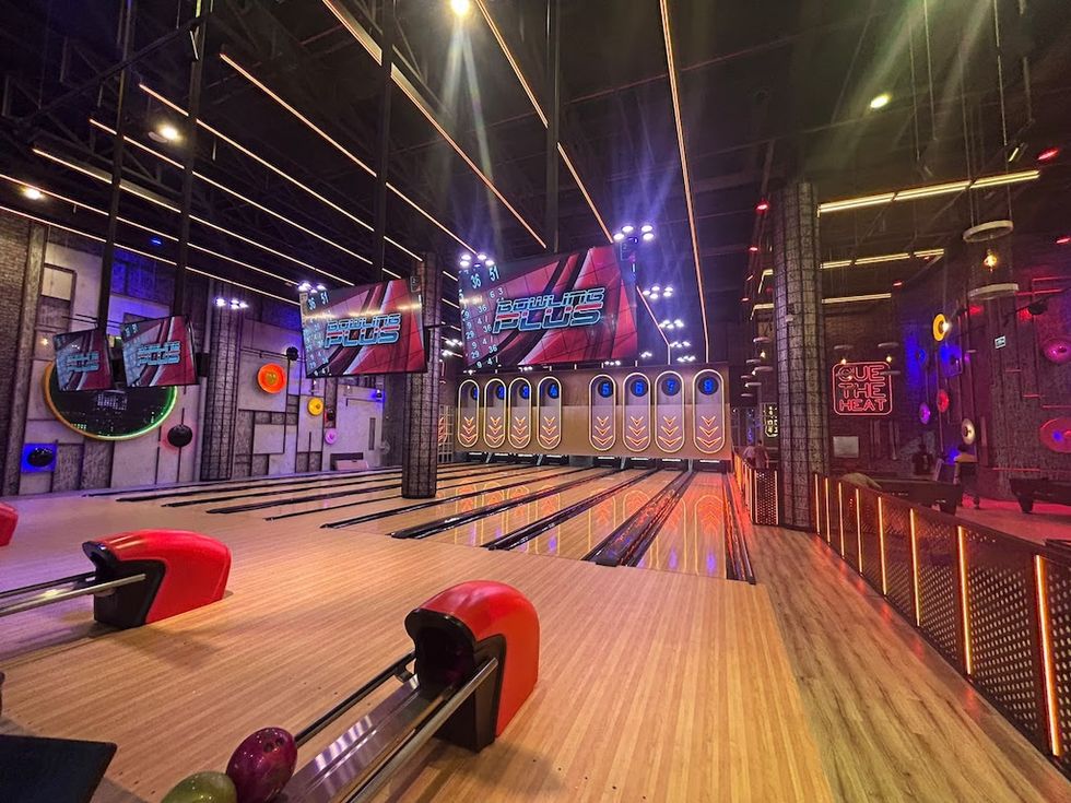 Vibrant bowling alley at BOLTS with colorful lights and digital scoreboards.