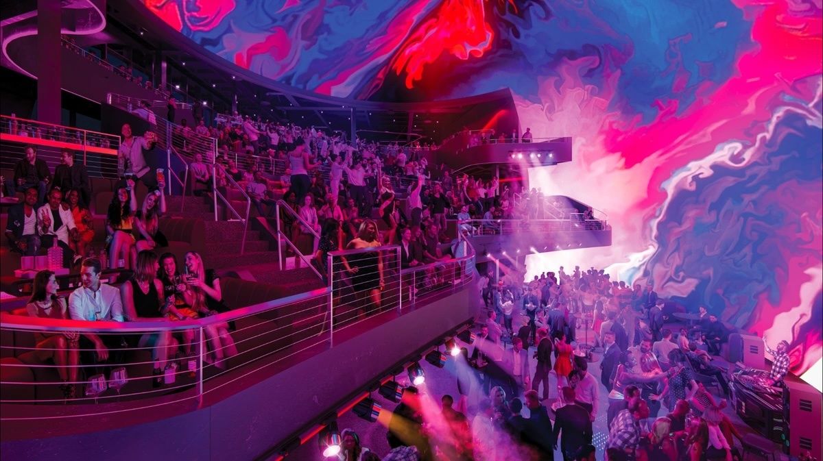 Vibrant club scene at Cosm venue with colorful digital art ceiling and a dancing crowd.