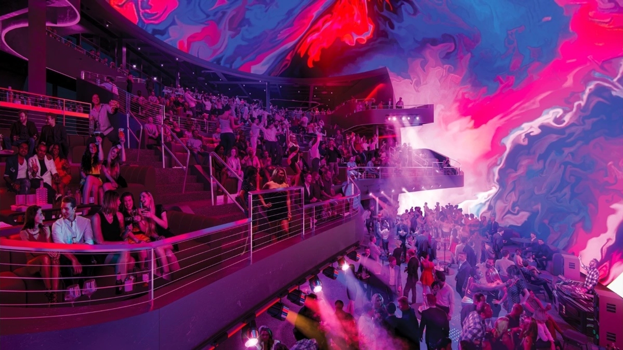 Vibrant club scene at Cosm venue with colorful digital art ceiling and a dancing crowd.