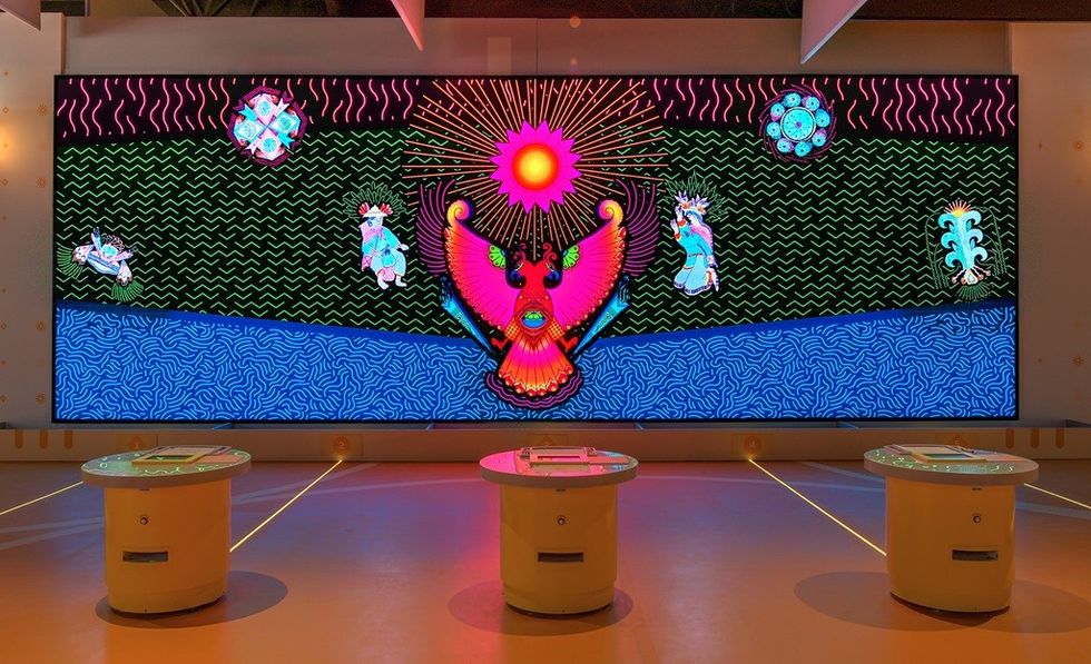 Vibrant digital art with mythical creatures and sunburst on a large screen display.