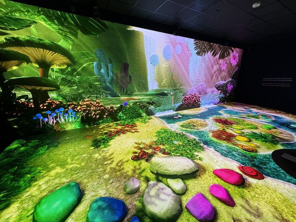 Vibrant digital forest with colorful giant plants and mushrooms in an immersive display.