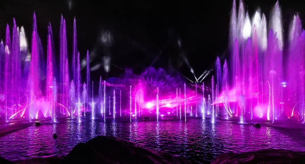 Vibrant fountains with pink lights in a nighttime water show.