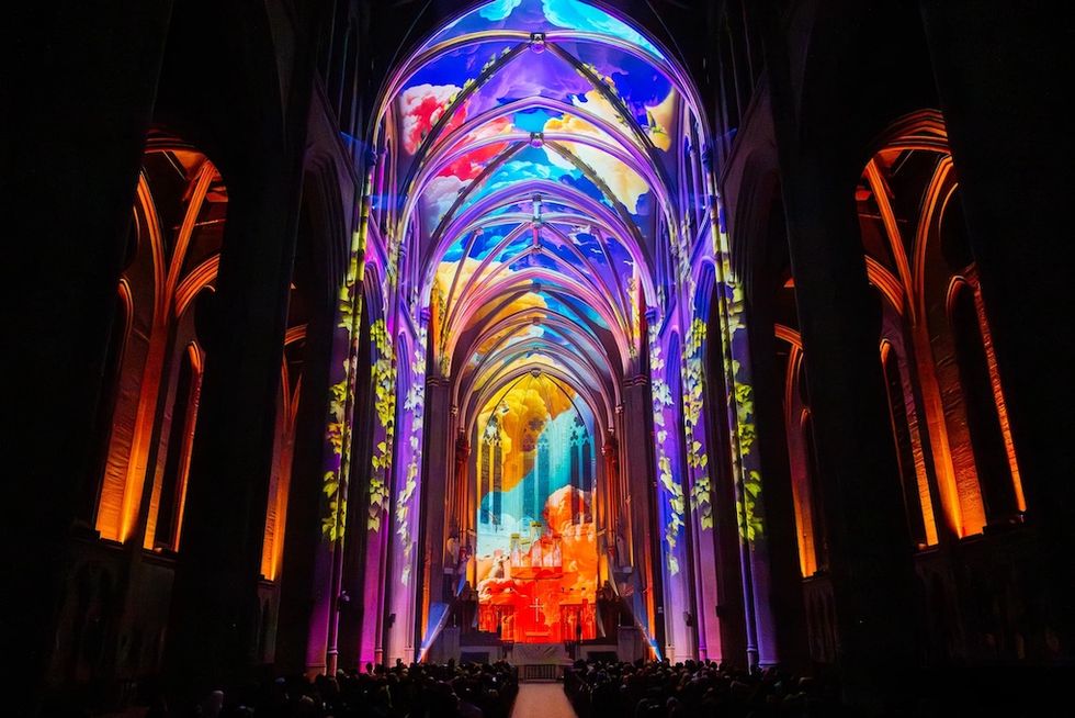 Vibrant light projections on cathedral interior with colorful, abstract designs.