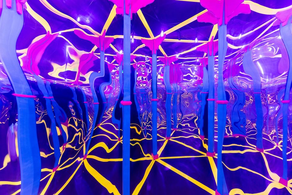 Vibrant mirrored room with twisting blue poles, pink accents, and yellow swirling patterns.
