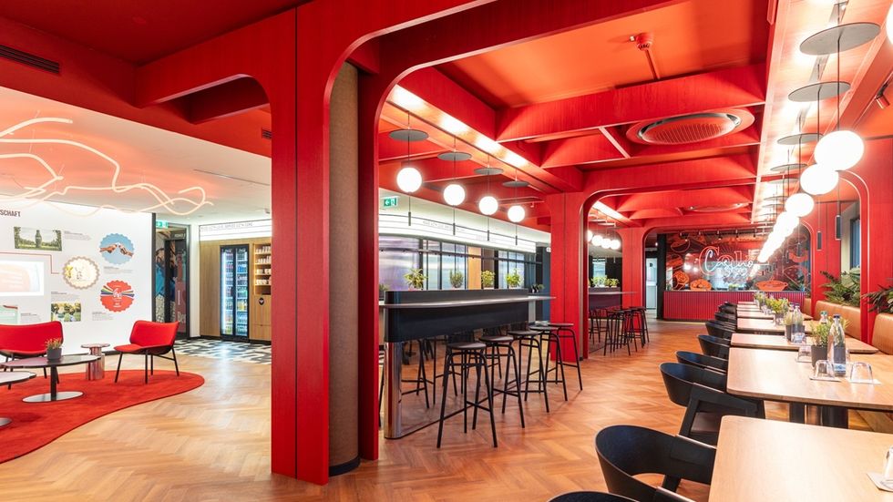 Vibrant red cafe with modern decor, tables, chairs, and ceiling lights at THE 6TH FLOOR in Berlin.