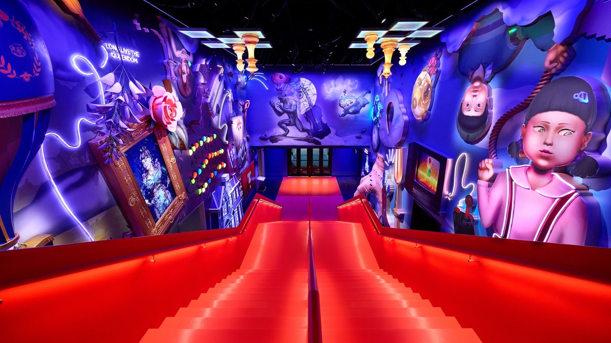 Vibrant, surreal hallway with red stairs and colorful murals on both walls.